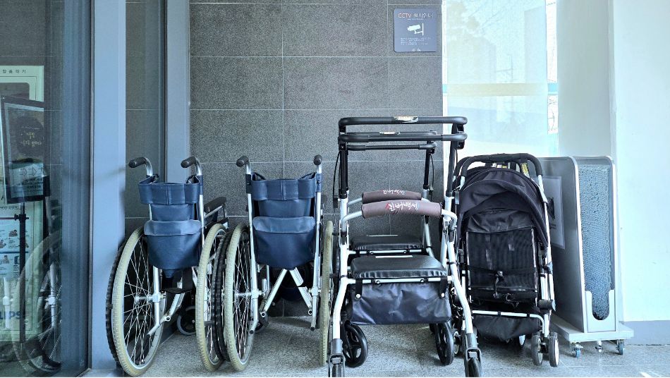 안내센터 입구 우측에 위치한 휠체어 2대, 유모차 3대, 보행보조기 2대가 구비된 사진입니다.