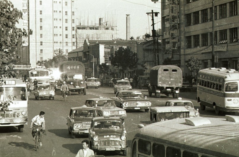 1967년대 서울시 한 도로를 촬영한 모습, 자전거, 트럭, 버스, 택시 등이 가득 차 혼잡스럽다.